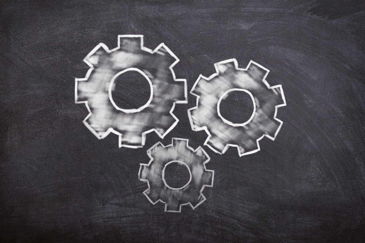 Three white gears on a chalk background